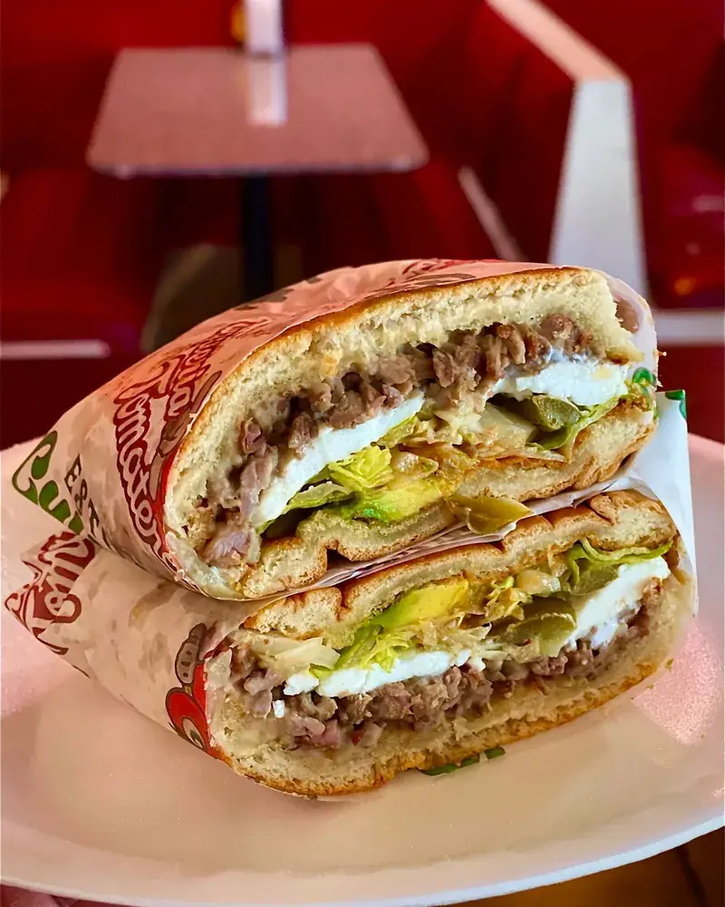 Torta cut in half showing grilled meat, cheese and avocado